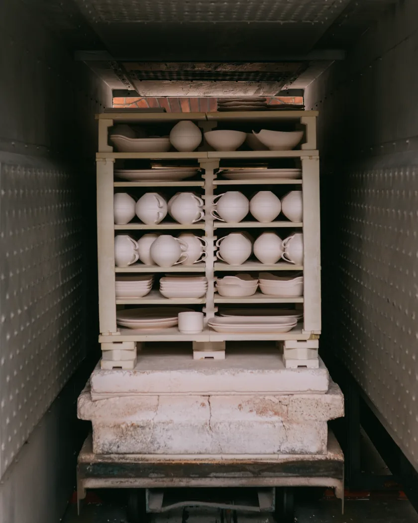 Platos de cerámica sin esmaltar colocados en vertical dentro de la cámara de un horno, separados entre sí antes de la cocción